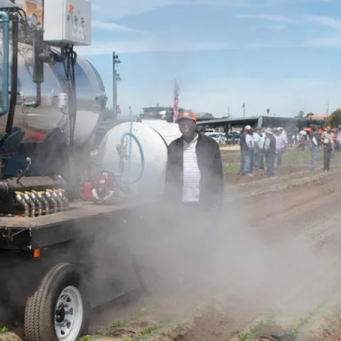 Postdoctoral researcher Connel Ching’anda stands by a machine that uses steam to disinfect soil of pathogens that can harm leafy green crops. Steve Fennimore and his team, of the UC Davis Department of Plant Sciences, tested the equipment last year in Salinas fields, and they demonstrated its use during Automated Technology Field Day, also in Salinas, in June. (Photo courtesy Jeffrey Mitchell/UC Davis)