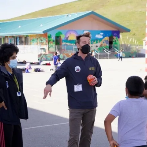 Teacher and students gathered around together during an active recess session.