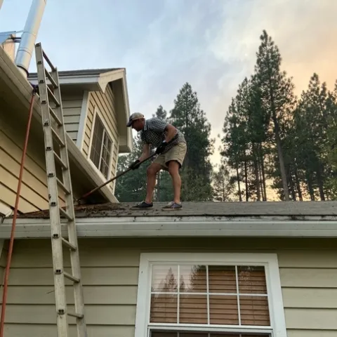 A man clears debris from his roof