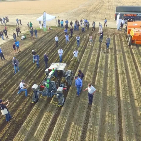 Aerial view of people and autonomous farm machinery on demo day at the Fresno State Farm.