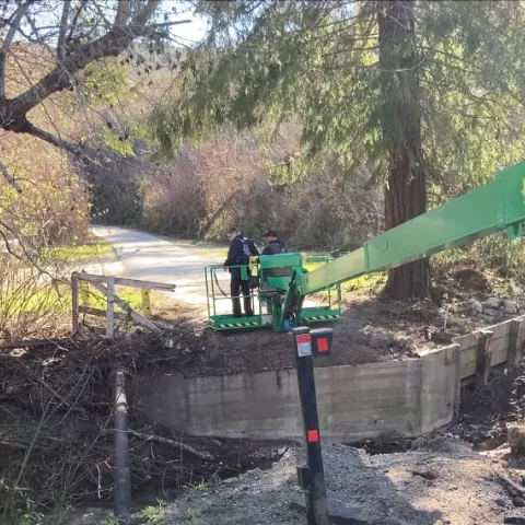 Two men stand on a green platform as the machine lowers them to the ground.