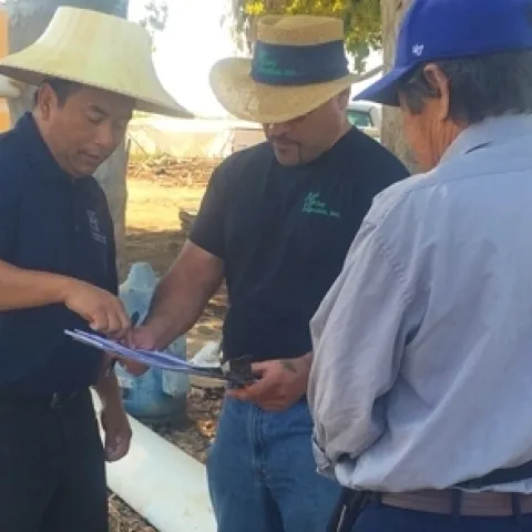 Michael Yang, left, discusses a new irrigation with a Hmong farmer. Photo by Ruth Dahlquist-Willard