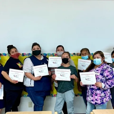 CAPSLO teachers stand in a line and hold their CATCH training certificate