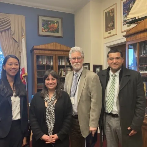The four people stand together in a congressional office.