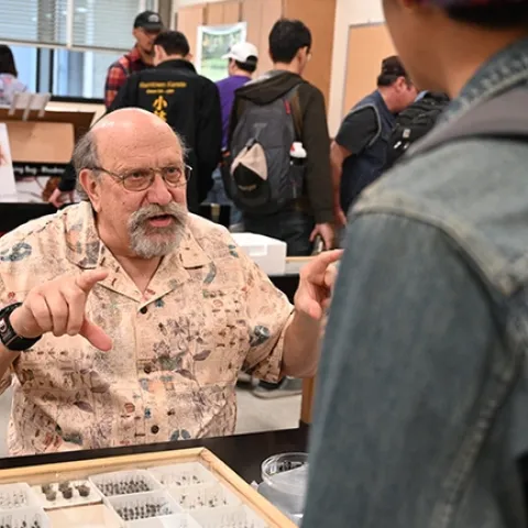 UC Davis forensic entomologist Robert "Bob" Kimsey explains his research. In back is a graphic of bed bugs. (Photo by Kathy Keatley Garvey)