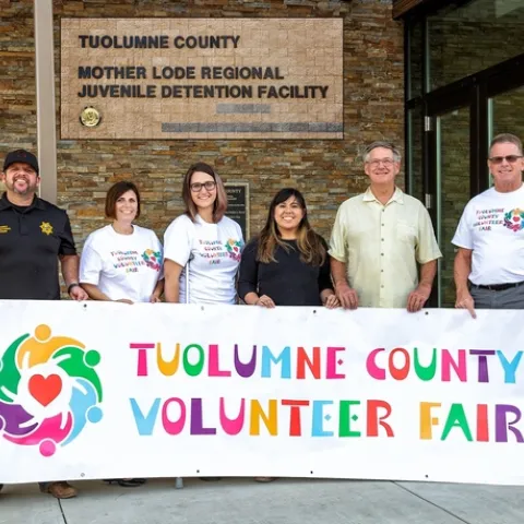 Volunteer Fair staff, Tuolumne County Probation Staff, and local volunteer stand behind Tuolumne County Volunteer Fair banner.