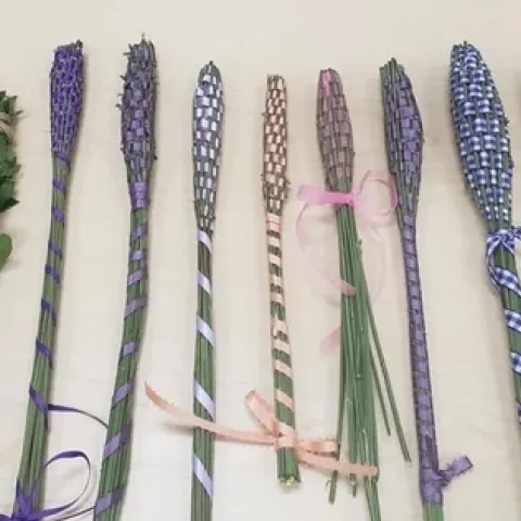 Nine wands of various colors (purple, pink, lavender) on display on a table.