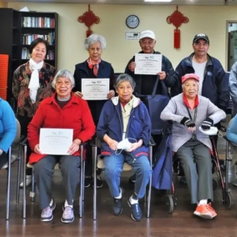A group of older adults and their instructor pose for a photo celebrating their completion of a six-week workshop series called Eat Healthy, Be Active.