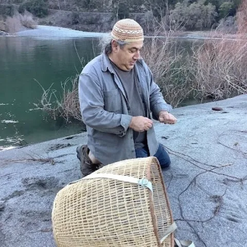 The Klamath River and trees are in background as Hillman harvests willow roots