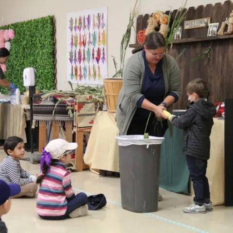Pies de grabado Stacey Amparano ayuda a sus jóvenes voluntarios a desgranar una mazorca.