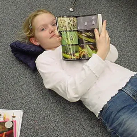 As a third grader, Jill Oberski is stretched out on the floor reading her "Audubon Field Guide to Insects and Spiders of North America." Another insect publication is within reach.