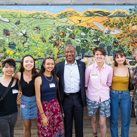 Posing for a celebratory photo are five mural participants with Chancellor Gary May and UC Davis distinguished professor Diane Ullman. From left are Kerry Lin, Sierra Deaver, Alia Tu, Chancellor May, Zoe Meilandt, Lily Nugent and Professor Ullman. (Photo courtesy of Jael Mackendorf, UC Davis College of Agricultural and Environmental Sciences)