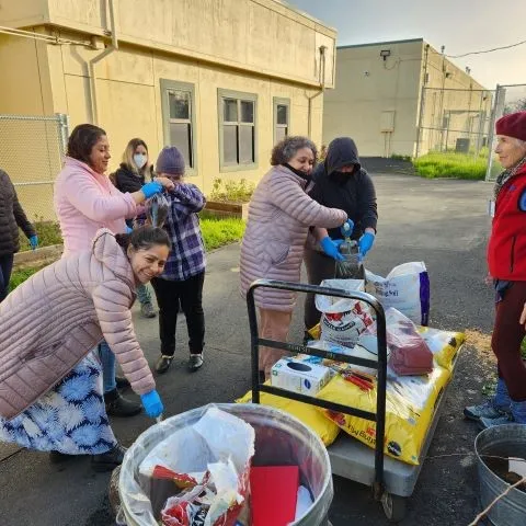Photo by Anne Sutherland. CoCoMG Rosalee Frankel hands out potting-up supplies to students at Monument Crisis Center Summer School.