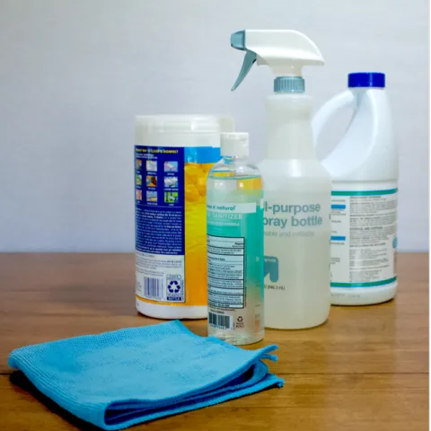 Several plastic bottles of cleaning solutions and a blue microfiber towel.