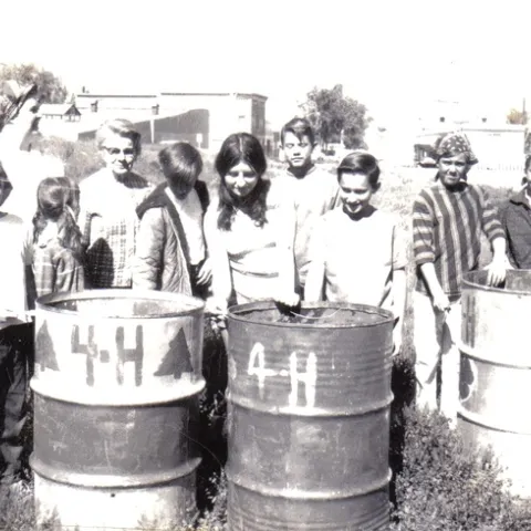 A black-and-white photo showing kids posing with painted trash cans