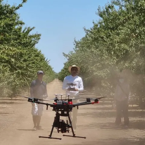 Person controls a drone as two other people look on