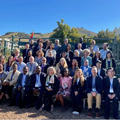 Forty one people sit in bleachers outdoors for group photo.