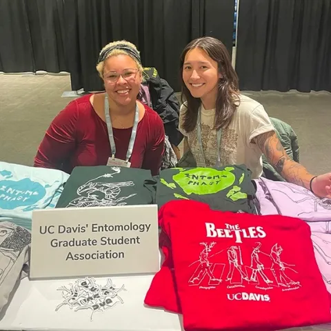 Doctoral students Mia Lippey (right) and Iris Quayle show some of the EGSA T-shirts for sale. Lippey is EGSA president, and Quayle, treasurer.