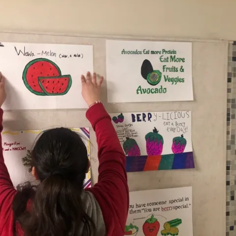 Hillview student adds her poster to the wall in one of the school's main hallways.