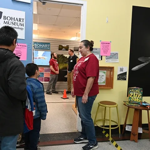 Bohart associate and entomologist, Nazzy Pakpour, PhD, author of "Please Don't Bite Me: Insects that Buzz, Bite and Sting," greets guests at the Bohart Museum. In back are Bohart director Jason Bond (right) conversing with Brennen Dyer, collections manager. (Photo by Kathy Keatley Garvey)