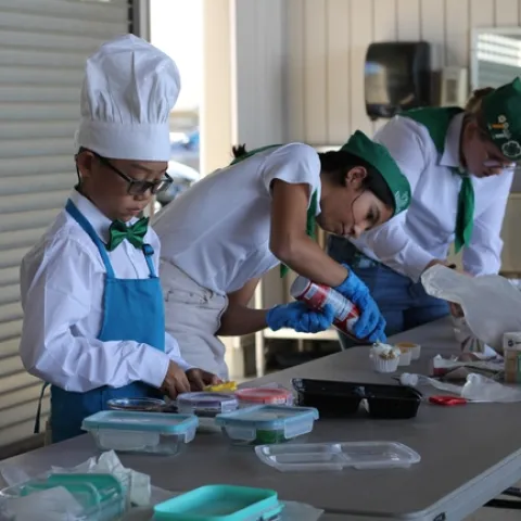Three youth decorate cupcakes.