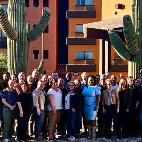 Group of people flanked by two large saguaro cacti.