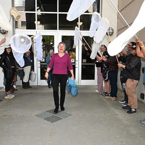 UC Davis distinguished professor emerita Lynn Kimsey walks under the archway of a 21-insect net salute. (Photo by Kathy Keatley Garvey)