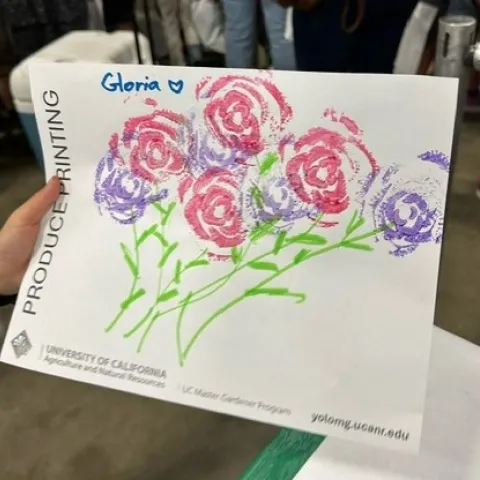 Paper with a bunch of red and purple rose-shaped flowers, with green leaves and stems.