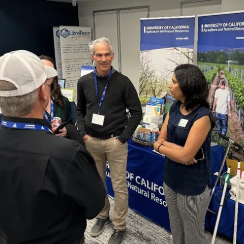Four people stand and converse at a display booth