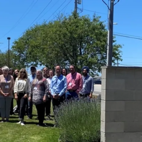 A group of a couple dozen people pose outdoors next to the "County of Monterey Agricultural Center 1428-1432 Abbott" sign.