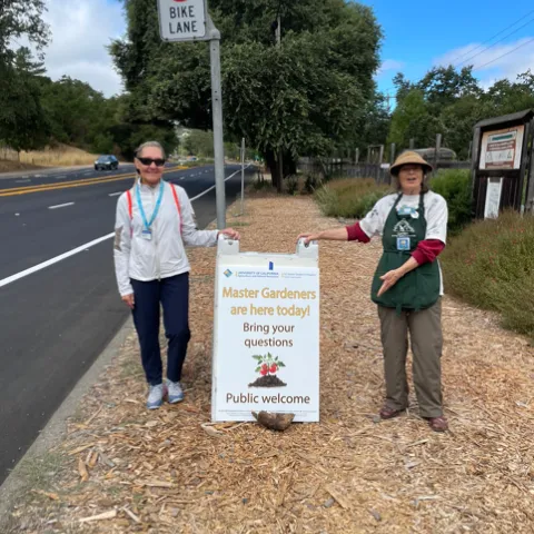 CoCoMGs Linda Mizes and Laura Callahan pose with new Community Gardens sign. Photo by UC Master Gardener.