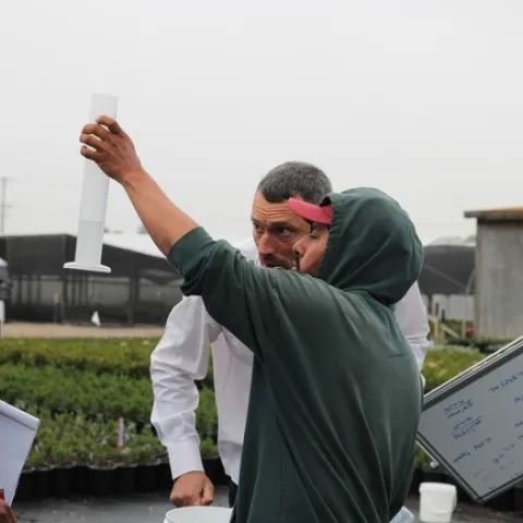 Gerry Spinelli (center) and an irrigator from Boething Treeland Farm confirm the amount of water captured from sprinklers. Photo by Saoimanu Sope.