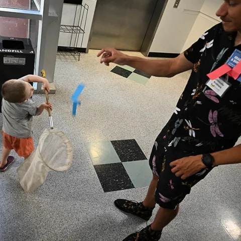Braden Nguyen, 3, of Davis, stretches to net a paper butterfly tossed by UC Davis doctoral student Christofer Brothers at the Bohart Museum of Entomology open house. (Photo by Kathy Keatley Garvey)