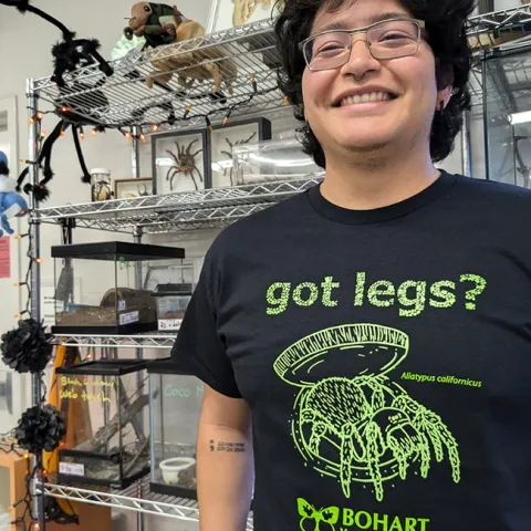 UC Davis student Jakob Lopez, a Bohart Museum employee, wearing the glow-in-the-dark trapdoor spider T-shirt. The cost is $22 plus tax for adult sizes and $18 plus tax for youth. Proceeds support the museum.