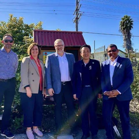 Five people standing in a garden under blue sky.