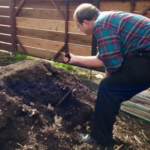 Rob Bennaton grabs a handful of top soil from a mound.