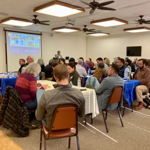 Swelam looks out to dozens of people seated at tables at West Side REC.