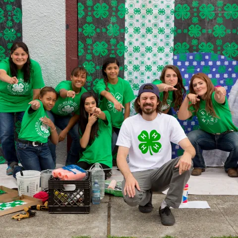 Adult posing with youth in front of wall they cleaned up