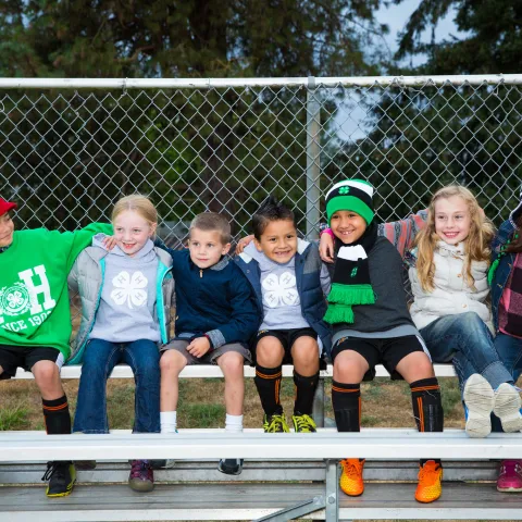 Group of Primary youth sitting next to each other on a bleacher