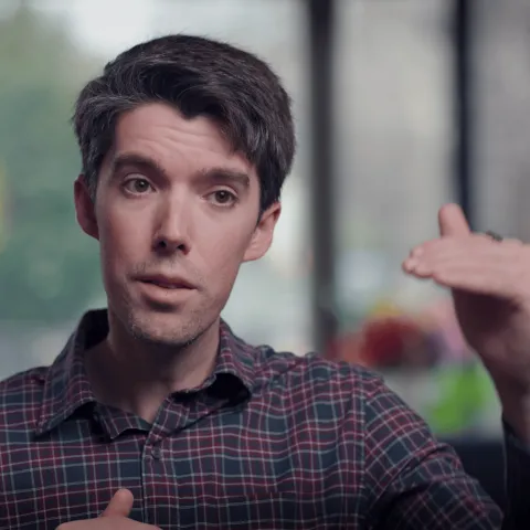 Daniel Swain, wearing a plaid shirt, gestures with his left hand 