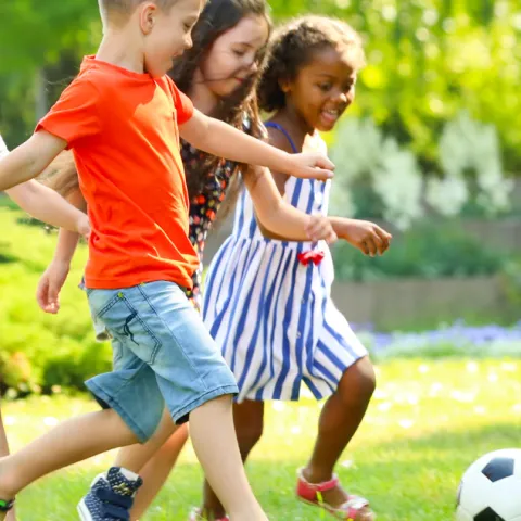 Children playing soccer in grass field