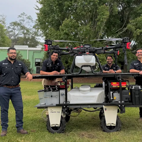 Five guys stand around a spray drone on an equipment stand. Headshots of a woman and two men are on the left side.