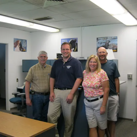 Four people stand in a row in an office