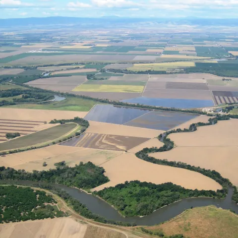 Ag fields between a winding river and mountains in the distance