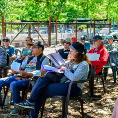 UC Master Gardener standing in a garden setting giving a talk to people sitting in chairs. 