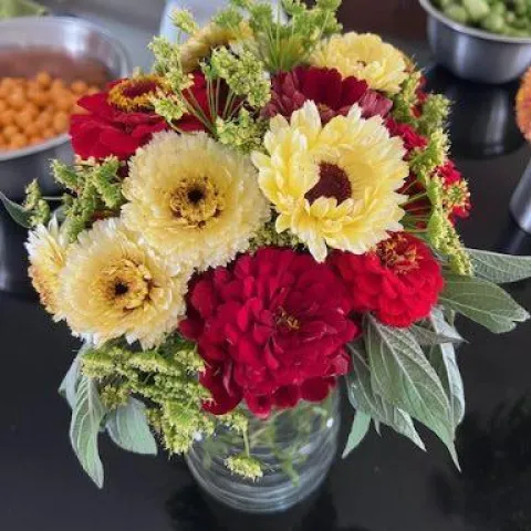 A bouquet of cream and red flowers in a vase.