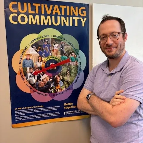 Scott Leaf standing in front of the Principles of Community Poster with a spinner attached