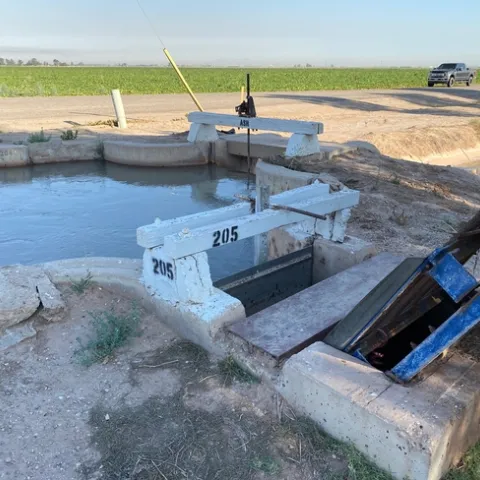 Water pump and small pool of water next to a crop field