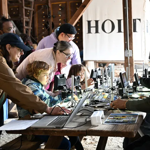 Families using microscopes to study organisms in UC Davis workshop.
