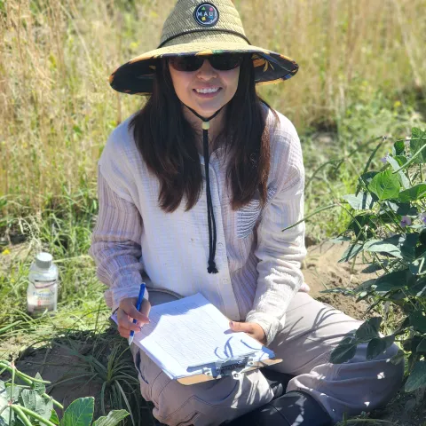 Ana sitting in field with sun hat